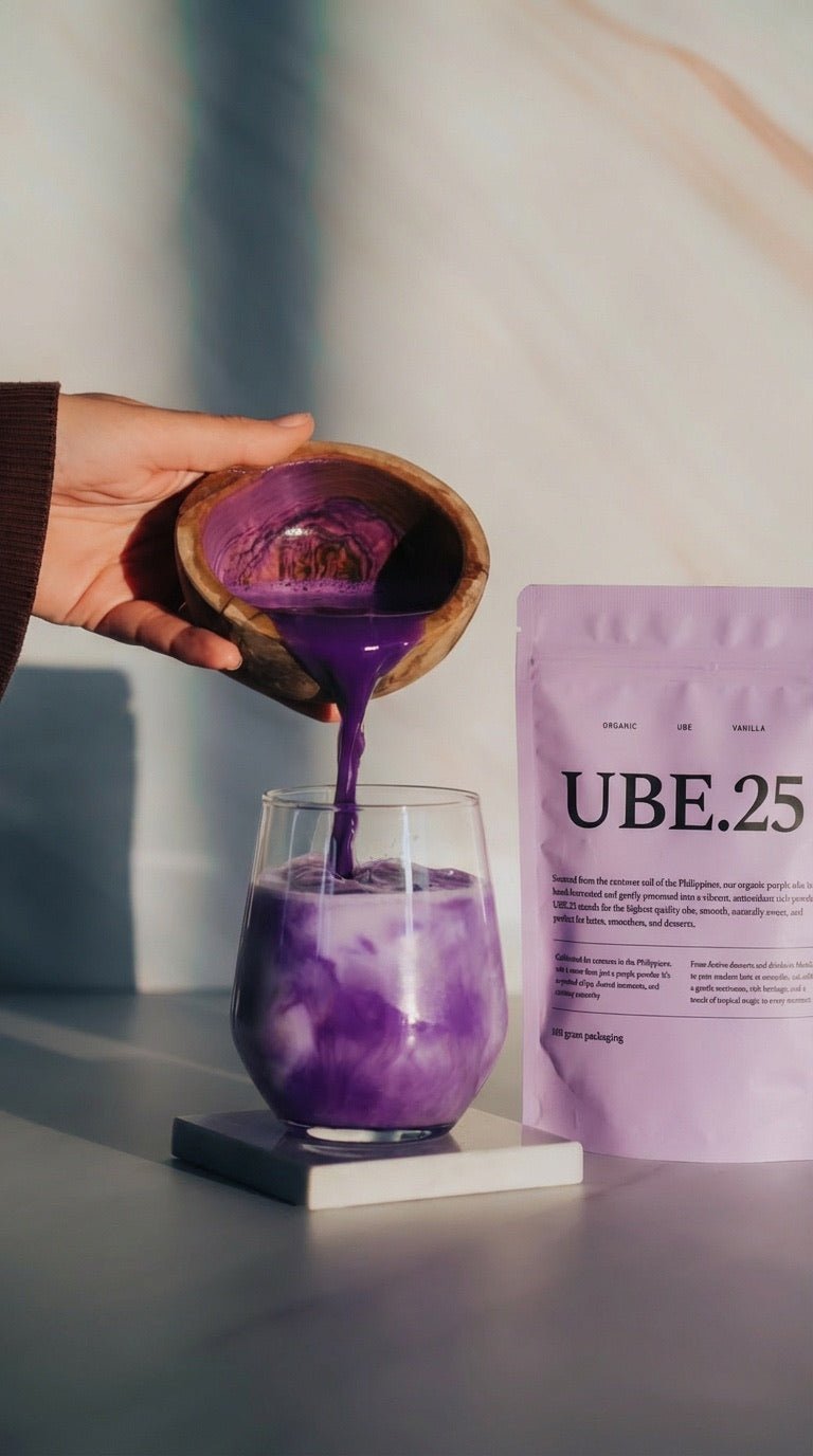 Ube powder being poured into a glass of milk next to a UBE.25 pouch
