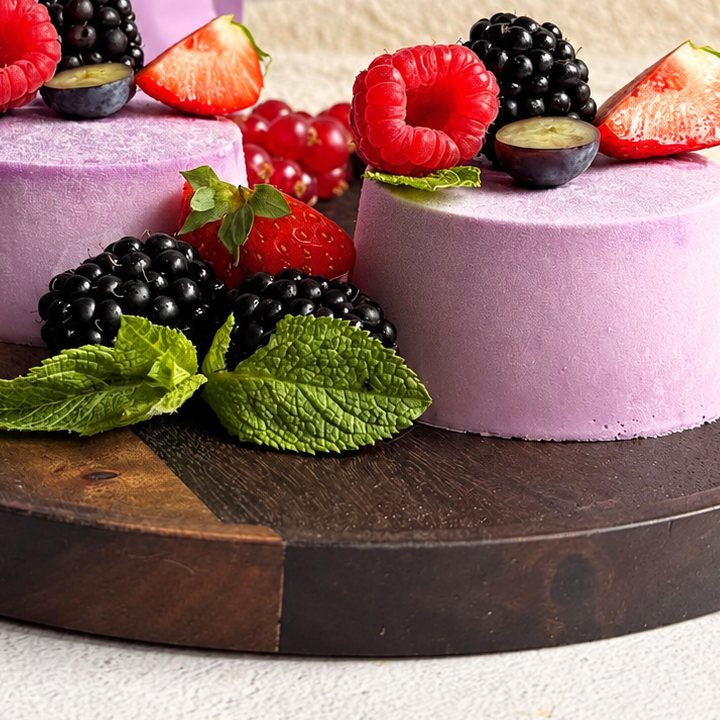 Ube panna cotta met rood fruit en munt op een houten serveerbord